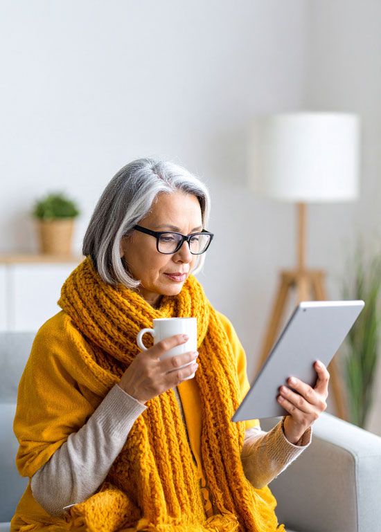 difference Femme âgée lisant une tablette, tasse à la main.