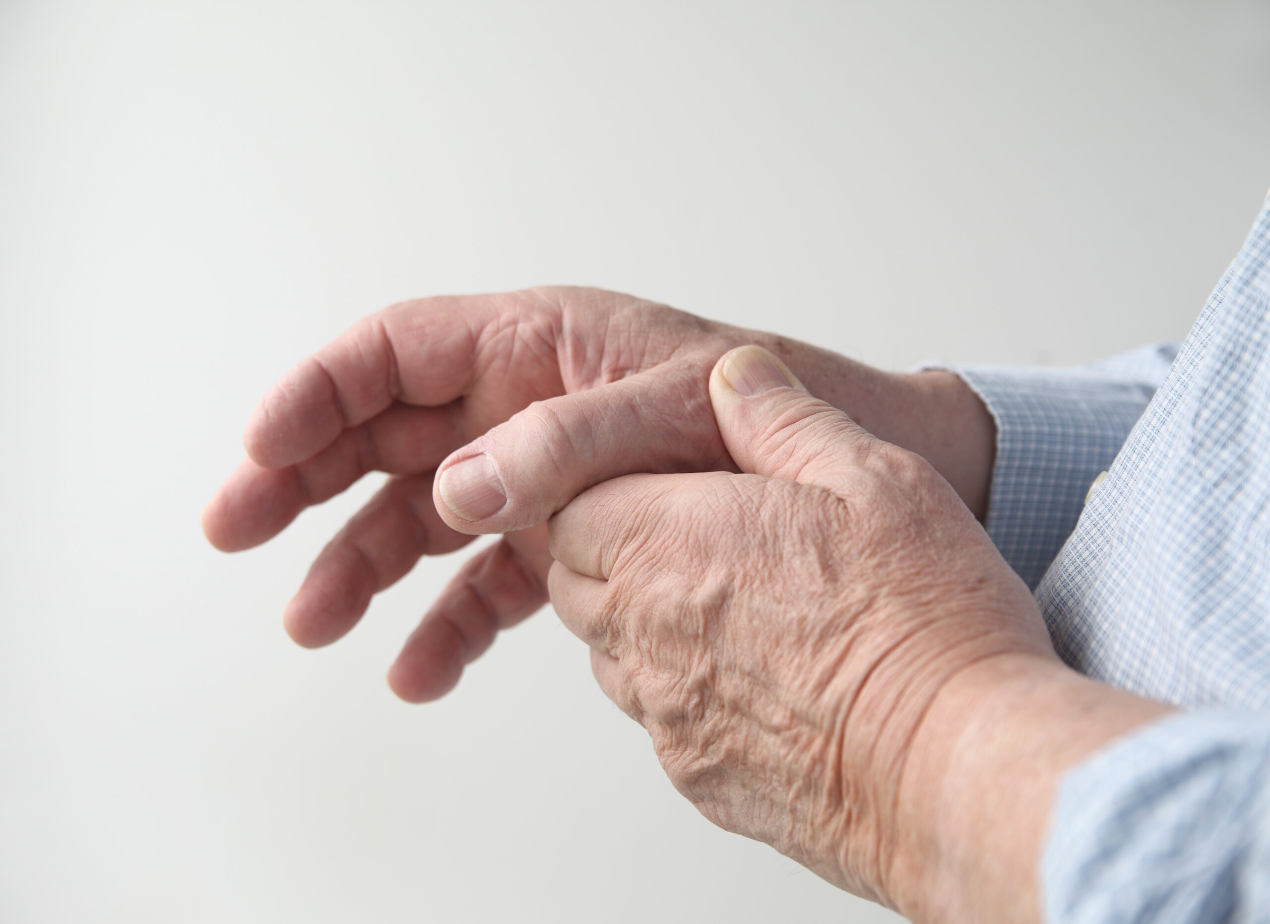 a man has pain in his thumb Deux mains âgées se touchent doucement.