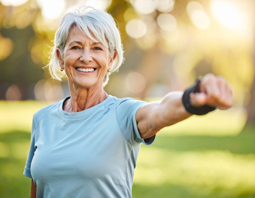 Laurence, 68 ans, fait des étirements doux dans un parc, 728547 Femme âgée souriante s'exerçant en plein air