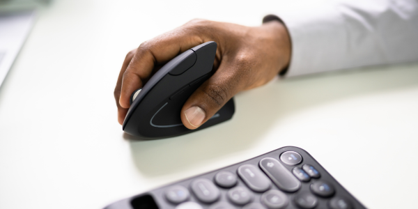 Main tenant une souris sur un bureau.