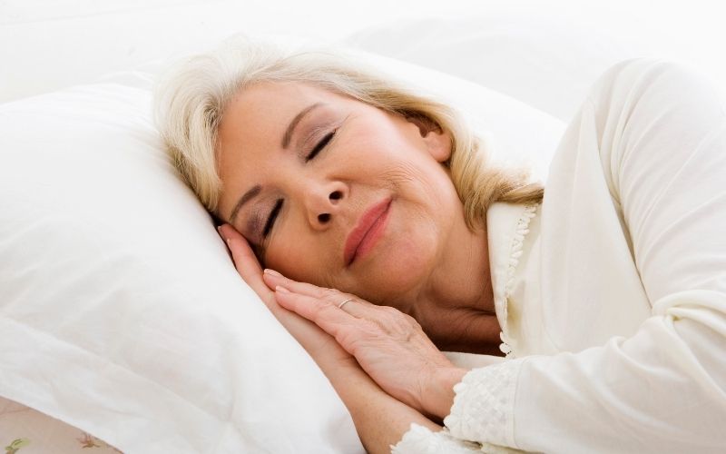 Femme âgée dormant paisiblement sur un oreiller.