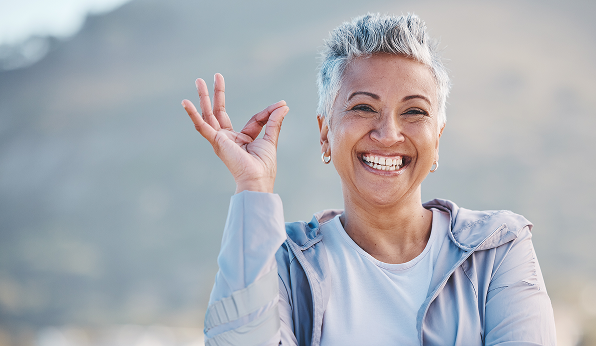Femme souriante avec une main levée.
