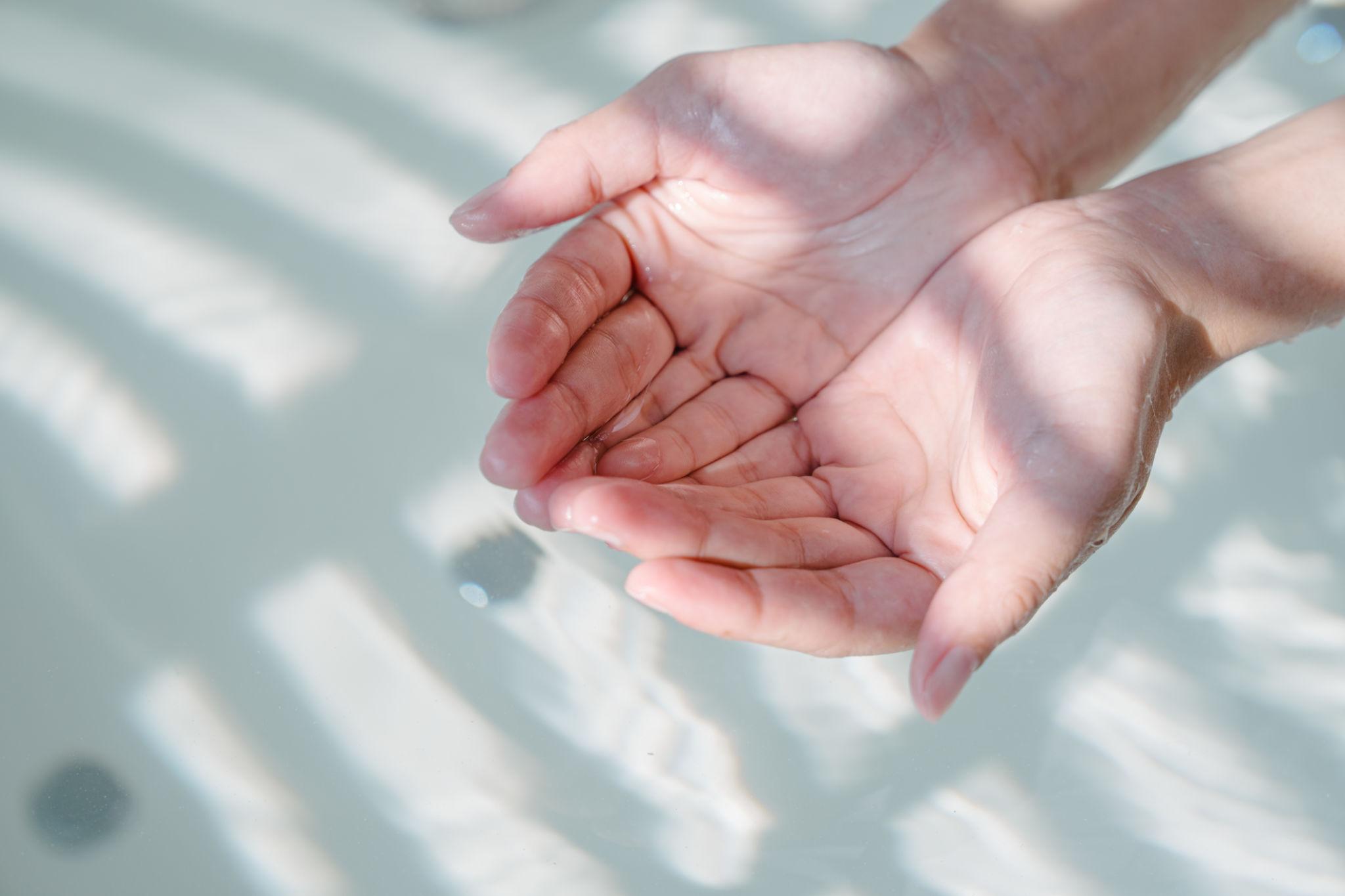 Mains ouvertes dans l'eau claire et lumineuse. arthrose et cures thermales