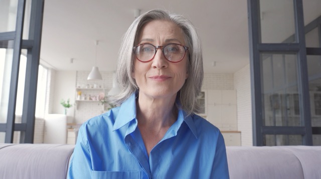 Femme souriante en chemise bleue, intérieur lumineux.